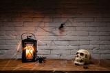 Skull and candle on a wooden table, spiders, cobweb brick wall background, halloween