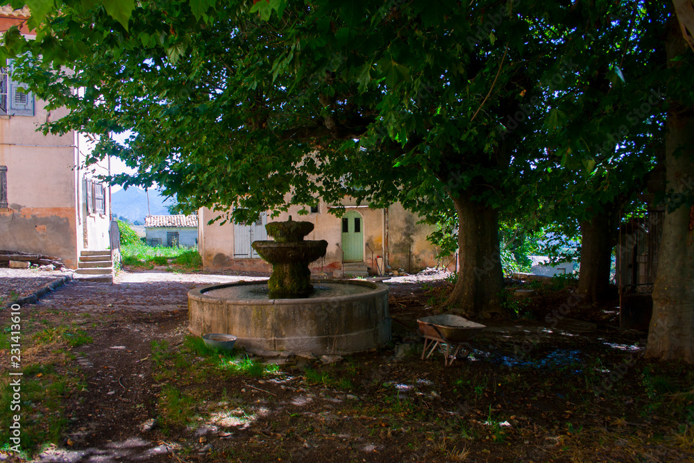 Villaggio abbandonato nel sud della Francia. Fontana e platani verdi.