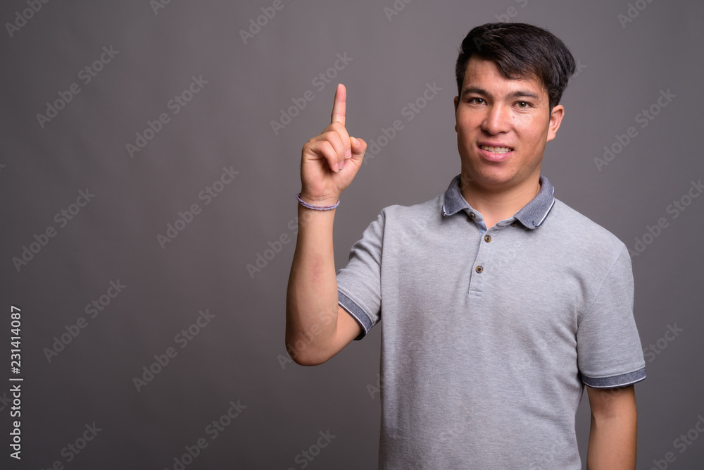 Portrait of young Asian man against gray background Portrait of young Asian man against gray background