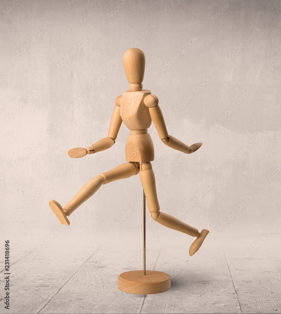 Wooden mannequin posed in front of a greyish background Wooden mannequin posed in front of a greyish background