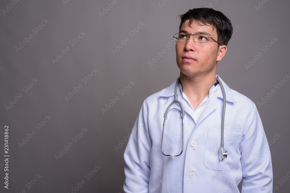 Young Asian man doctor against gray background Young Asian man doctor against gray background