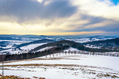 Majestic winter landscape with snow and dramatic sky in Rhön Mountains, Germany