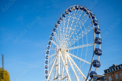 Low angle view of white structure and blue cabin of Ferris wheel with background of clear blue sunny sky. © Peeradontax