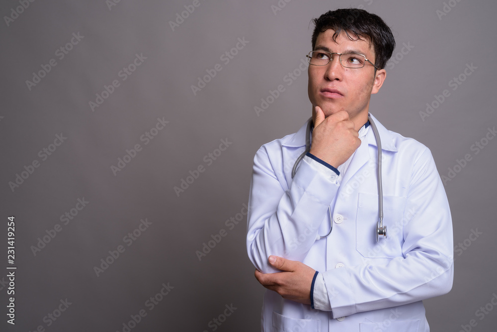 Young Asian man doctor against gray background Young Asian man doctor against gray background
