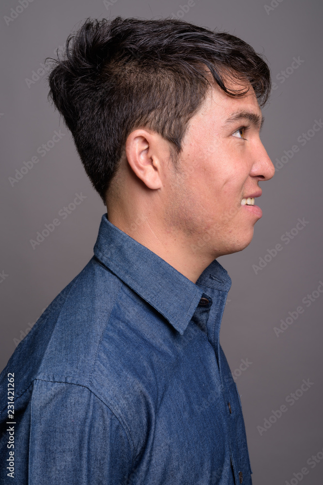 Fototapeta premium Young Asian man wearing blue shirt against gray background