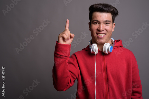 Young Asian man wearing headphones against gray background