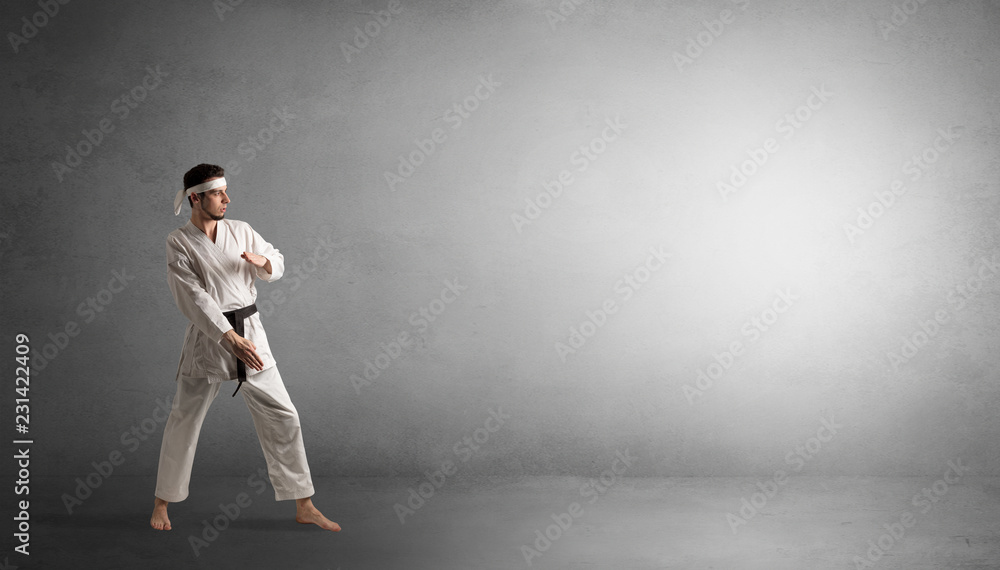 Small karate man fighting in an empty grey copy space Small karate man fighting in an empty grey copy space