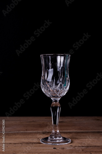 Elegant liqueur glass on wooden table with black wall background