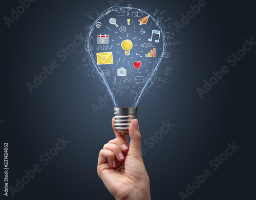 Hand holding light bulb on dark background. New apps concept