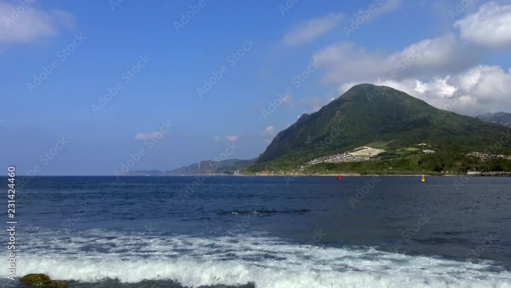 4K, Sea waves beach view with Keelung mountain of background in New Taipei city. Coastline seascape with mountains and blue sky. Seashore at beautiful day of summer in Jishan-Dan 4K, Sea waves beach view with Keelung mountain of background in New Taipei city. Coastline seascape with mountains and blue sky. Seashore at beautiful day of summer in Jishan-Dan