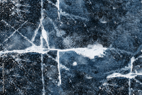 The texture of the ice on the river, lake: a large white cracks in the blue ice. Cracking ice.