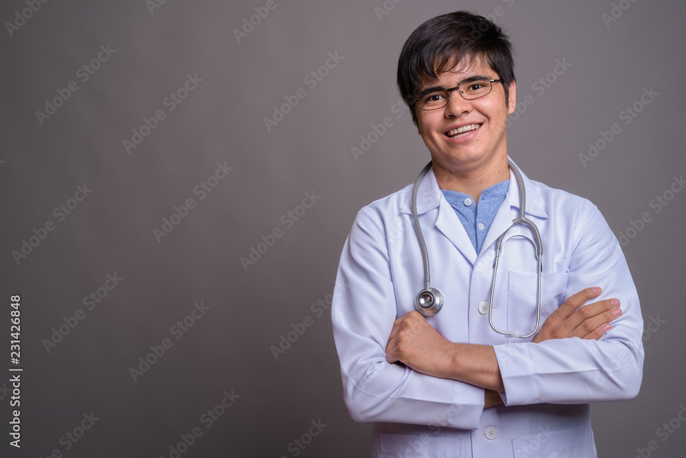 Young Asian man doctor against gray background Young Asian man doctor against gray background