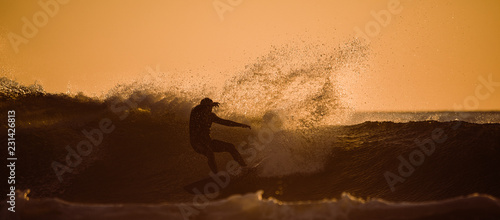 silhouette of man surfing at sunset