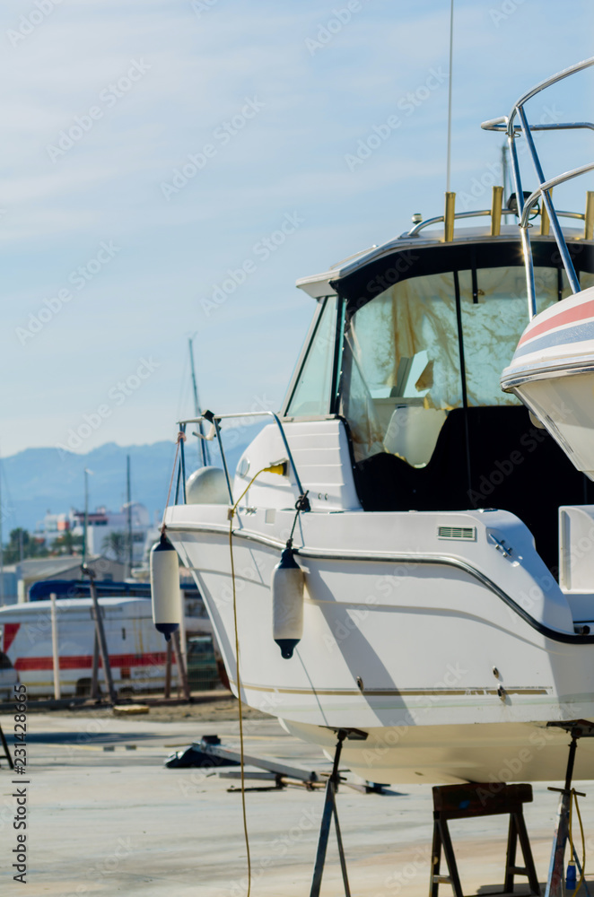 Fototapeta premium Boat on stand on the shore, close up on the part of the yacht, luxury ship, maintenance and parking place boat
