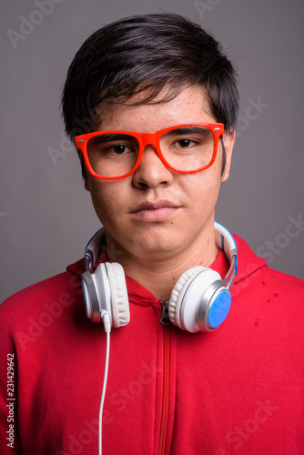 Young Asian teenage boy wearing headphones against gray backgrou