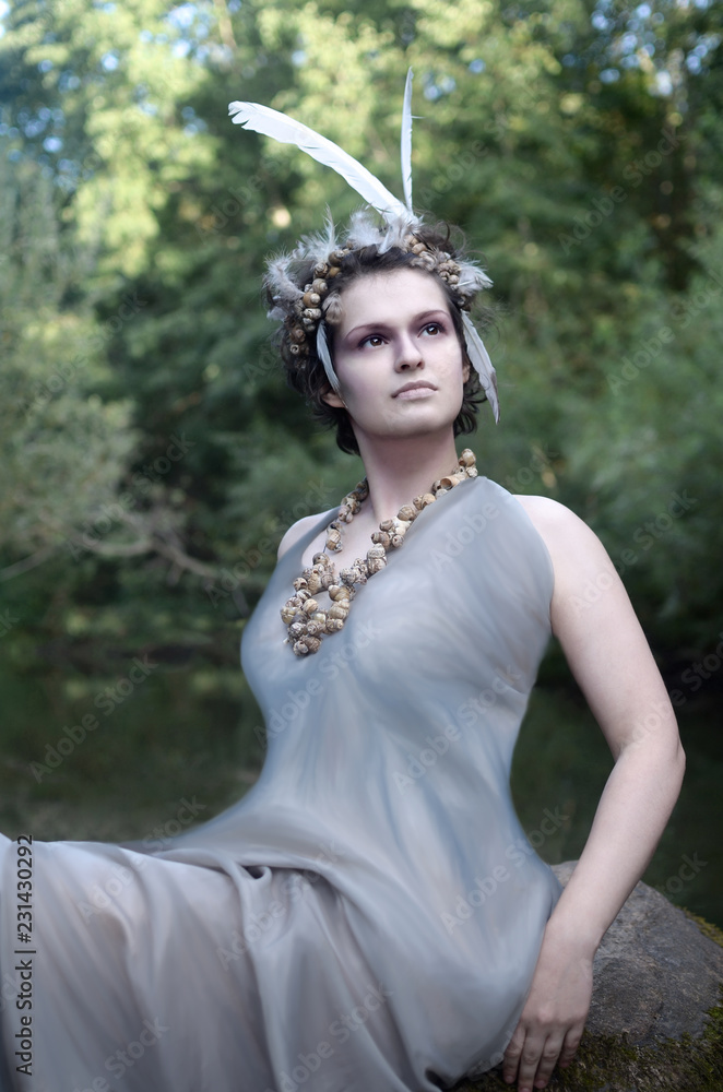 Φωτογραφία portrait of a young woman in a wreath of sea snail shells and feathers