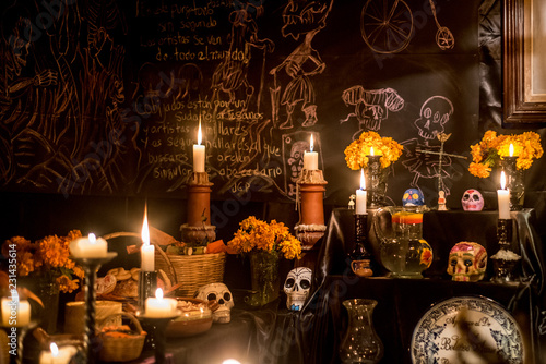 ofrenda mexicana altar de dia de muertos con velas calaveras y flores de cempasuchil fondo negro y letras blancas photo
