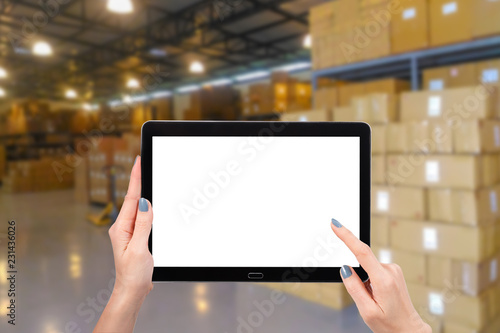 Hand using mock up computer tablet on warehouse background, with copy space