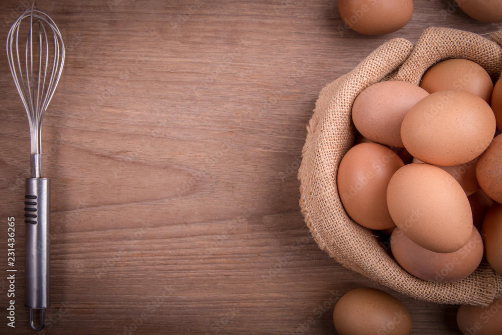 Fresh farm eggs on a wooden rustic background, Whipping eggs and whisk,top view with copy space Fresh farm eggs on a wooden rustic background, Whipping eggs and whisk,top view with copy space