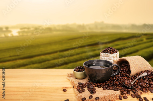 Hot cup of coffee and beans with burlap sack on the wooden table, with copy space