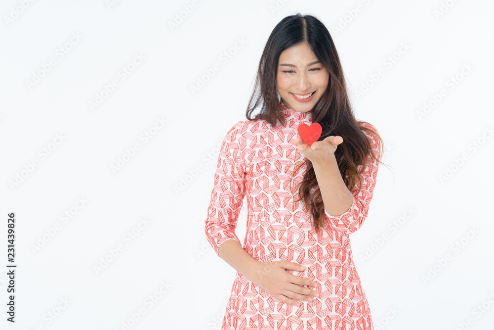Photo of asian curious woman in red dress rejoicing her birthday or new year. Young woman holding red heart being excited and surprised holiday present isolated white background Photo of asian curious woman in red dress rejoicing her birthday or new year. Young woman holding red heart being excited and surprised holiday present isolated white background