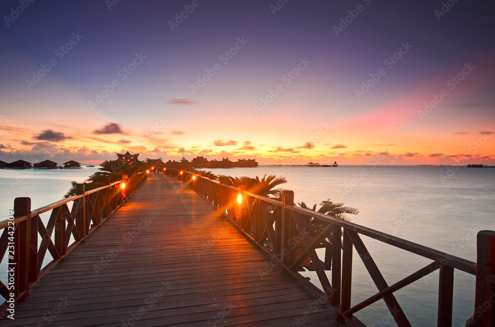 Obraz premium Long bridge heading to beautiful resort at Mabul Island during sunset.