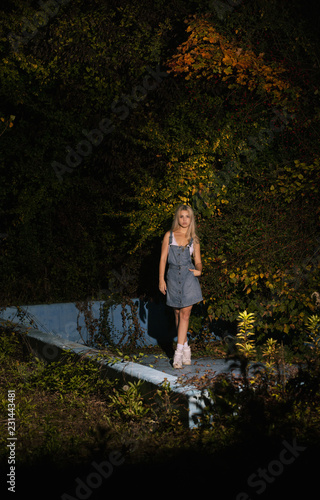 Young girl in jeans skirt posing in abandoned swimming poll