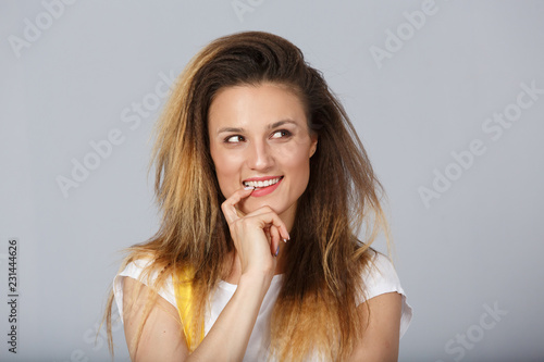Headshot of tricky beautiful woman with curly long-hair style touching lips, looking aside with cunning smile and having some ideas in her mind. Attractive female having sly expression