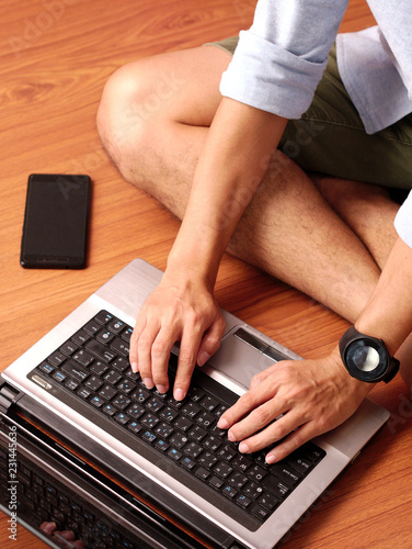 Wallpaper Mural Closeup of a man sitting typing on laptop wearing smart-watch and mobilephone beside. Torontodigital.ca