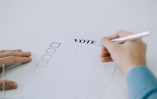 Hand with pen and check box for voting.