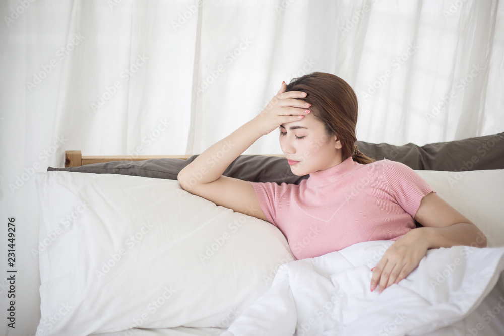 Young asian woman touching her forehead on the bed. Woman sick concepts : headache, dizziness, fever. Young asian woman touching her forehead on the bed. Woman sick concepts : headache, dizziness, fever.