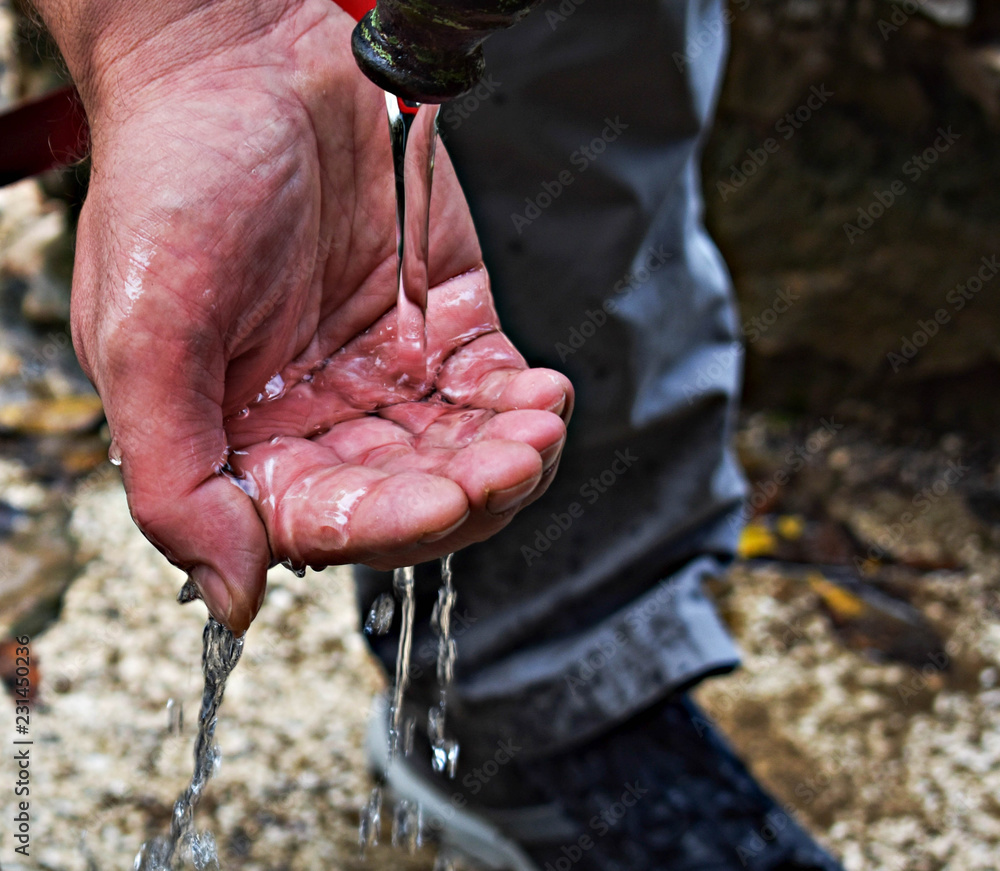 Stream of clean water pouring into man`s hand/ Hands catching clean falling water close up. Environmental concept.
