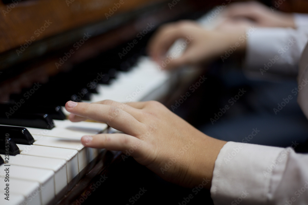 Fototapeta premium Children play piano in four hands
