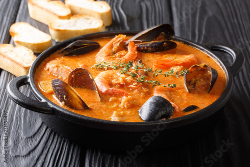 Seafood spicy soup with potatoes, shrimps, mussels, herbs and fish from a picad closeup served with toast. horizontal