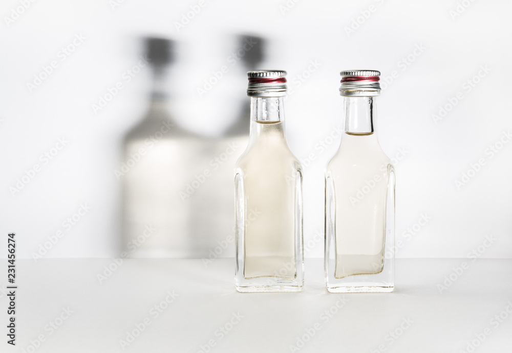 Two bottles of vintage alcohol with shadows on the wall.
