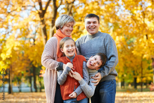 Happy family walks in autumn city park. Children and parents posing, smiling, playing and having fun. Bright yellow trees. © soleg