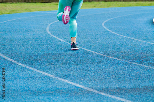 female athlete running on the blue running track outdoors