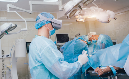 Doctor in a surgical room with virtual reality glasses on the background of the real operation.