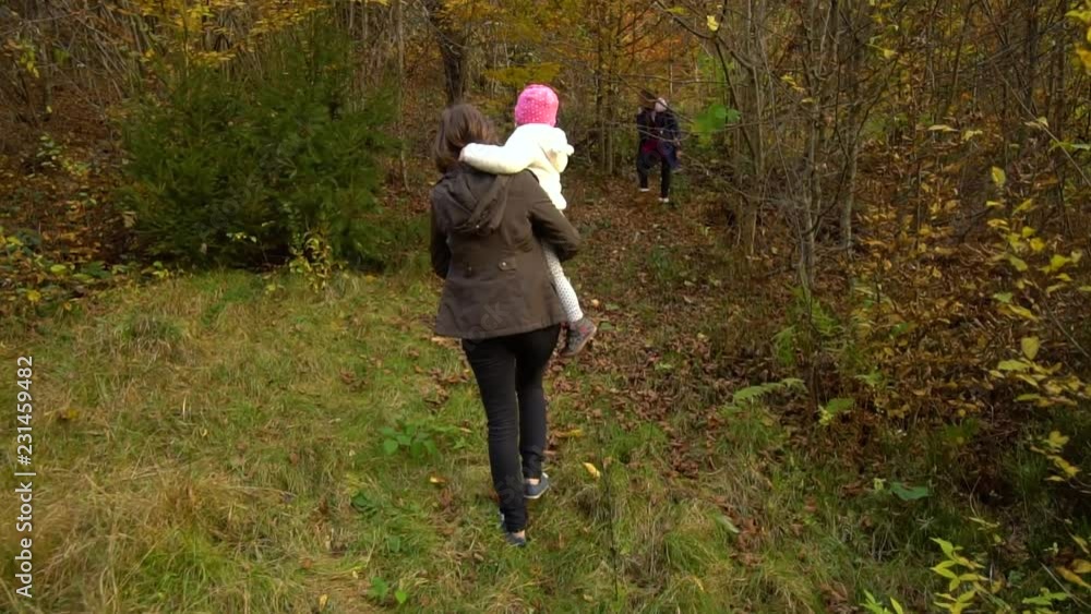 A young mother with her two children walks through the autumn forest. They enter a dense impassable forest. Slow motion. A young mother with her two children walks through the autumn forest. They enter a dense impassable forest. Slow motion.