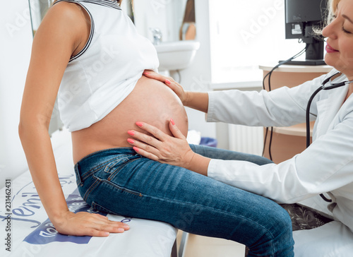 A gynecologist examines a pregnant woman. Patient at doctor office. Pregnant woman at hospital.