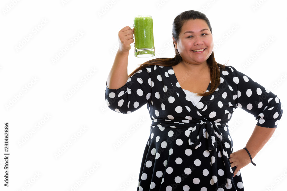 Studio shot of young happy fat Asian woman smiling while raising Studio shot of young happy fat Asian woman smiling while raising