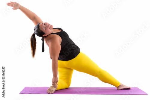 Studio shot of young happy fat Asian woman smiling and bending b