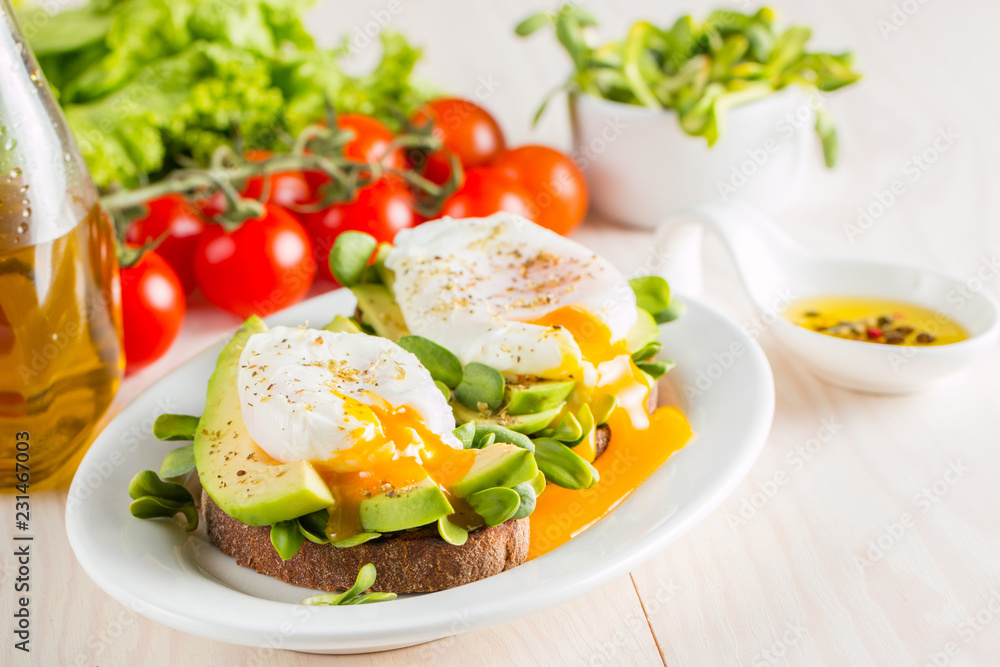 Avocado toast, cherry tomato and poached eggs on wooden background. Breakfast with vegetarian food, healthy diet concept.