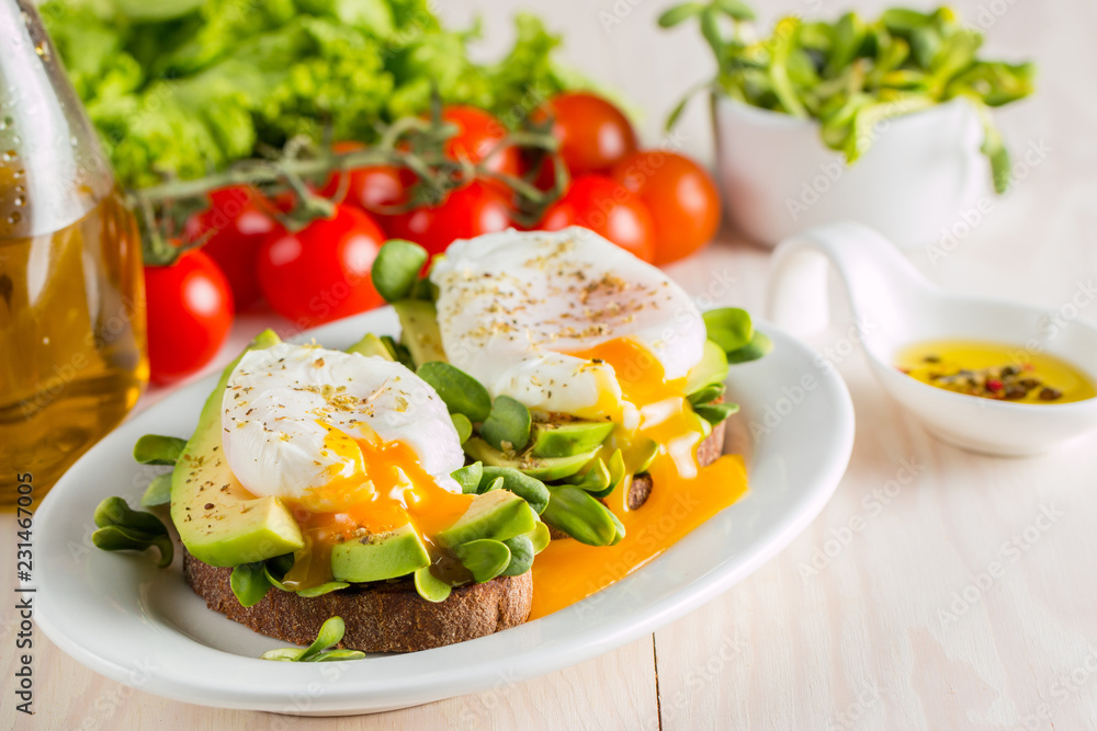 Avocado toast, cherry tomato and poached eggs on wooden background. Breakfast with vegetarian food, healthy diet concept.