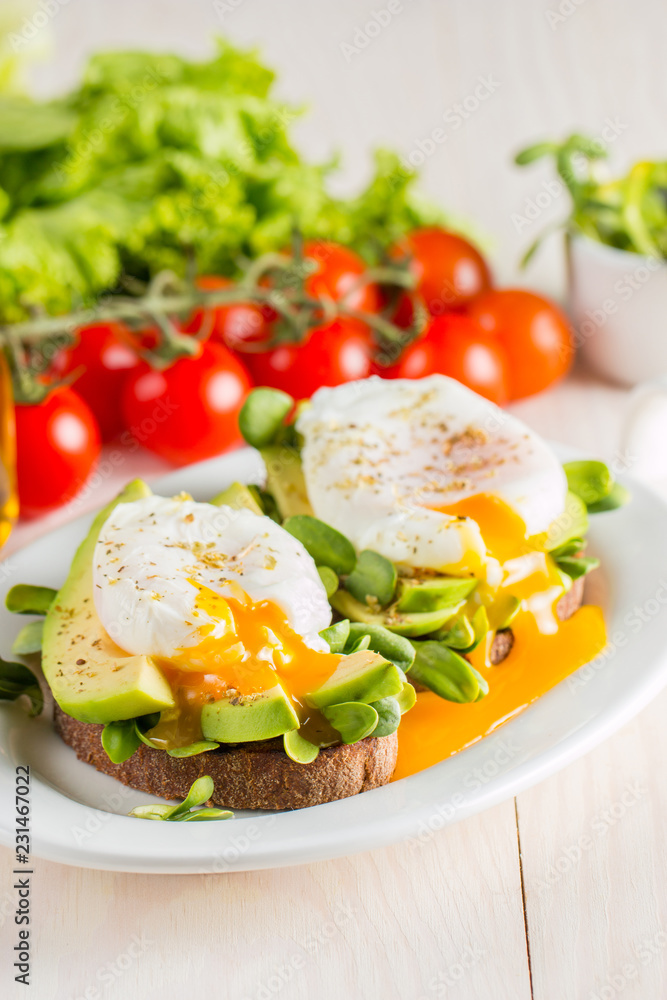 Avocado toast, cherry tomato and poached eggs on wooden background. Breakfast with vegetarian food, healthy diet concept. Avocado toast, cherry tomato and poached eggs on wooden background. Breakfast with vegetarian food, healthy diet concept.