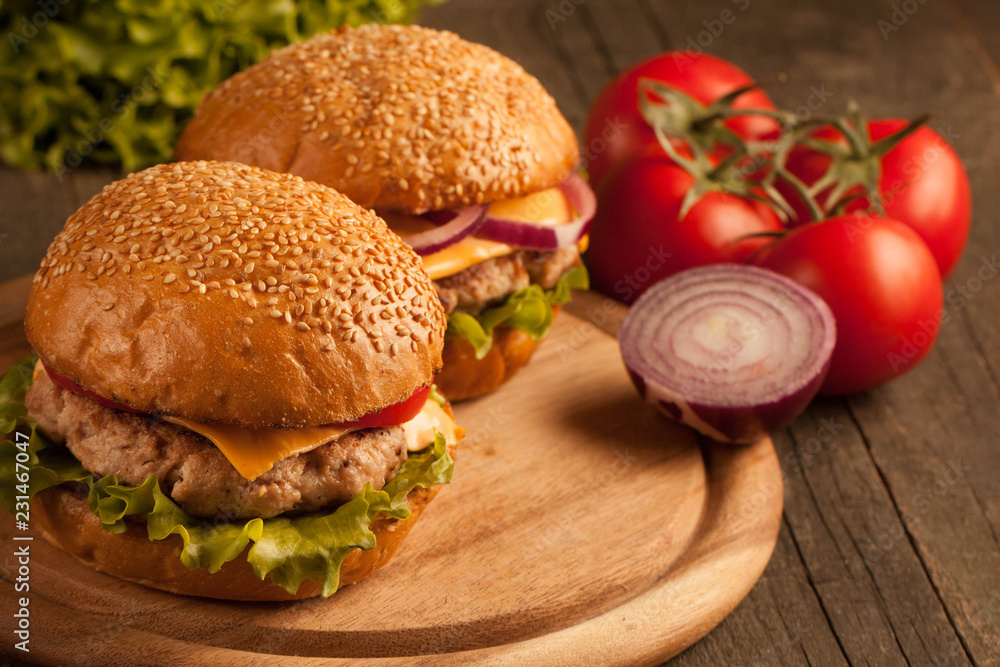Home made hamburger with beef, onion, tomato, lettuce and cheese. Fresh burger close up on wooden rustic table with potato fries, beer and chips. Cheeseburger. Home made hamburger with beef, onion, tomato, lettuce and cheese. Fresh burger close up on wooden rustic table with potato fries, beer and chips. Cheeseburger.