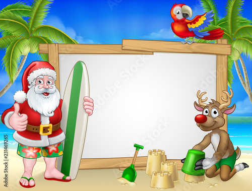 Santa Claus Christmas cartoon character in shorts and flip flops holding his surfboard on a tropical beach with his reindeer making sandcastles sign background.