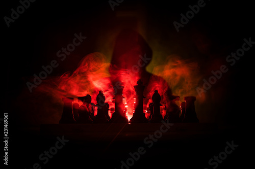 Man playing chess. Scary blurred silhouette of a person at the chessboard with chess figures. Dark toned foggy background. © zef art