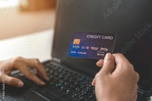 Close up of young asian woman hand holding credit card and use laptop for purchase product on internet in home office, Cyber Monday shopping online concept.