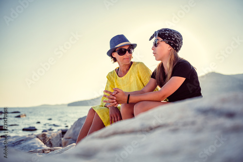 Mother and daughter talking on a rocky beach